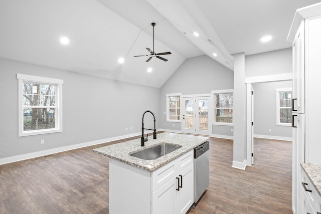 kitchen featuring sink, dishwasher, white cabinetry, light stone counters, and a center island with sink