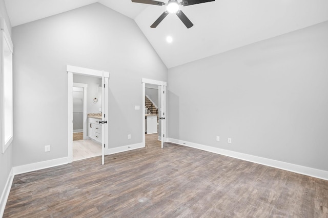 unfurnished bedroom featuring ceiling fan, wood-type flooring, ensuite bathroom, and high vaulted ceiling