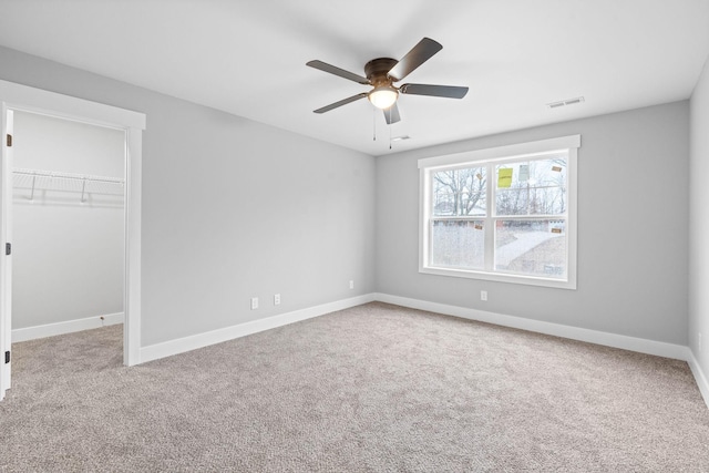 unfurnished bedroom featuring carpet, a spacious closet, ceiling fan, and a closet