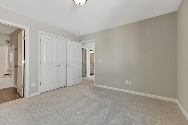 unfurnished bedroom with light colored carpet, connected bathroom, and a closet