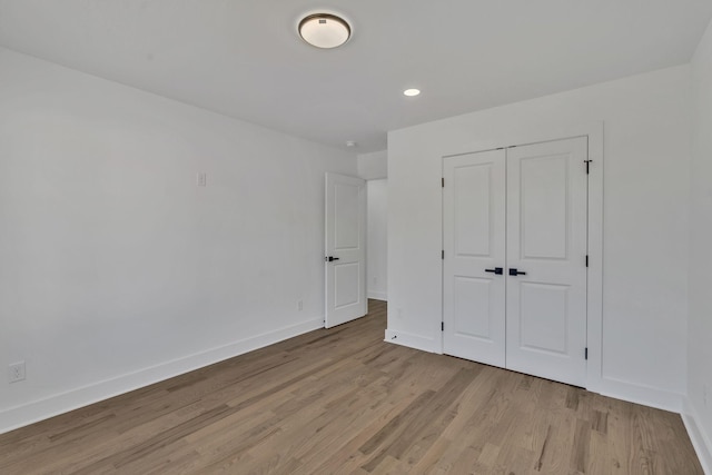 unfurnished bedroom with light wood-type flooring and a closet