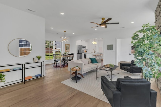 living room featuring hardwood / wood-style flooring, sink, and ceiling fan with notable chandelier