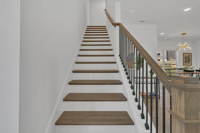 stairway with an inviting chandelier and wood-type flooring