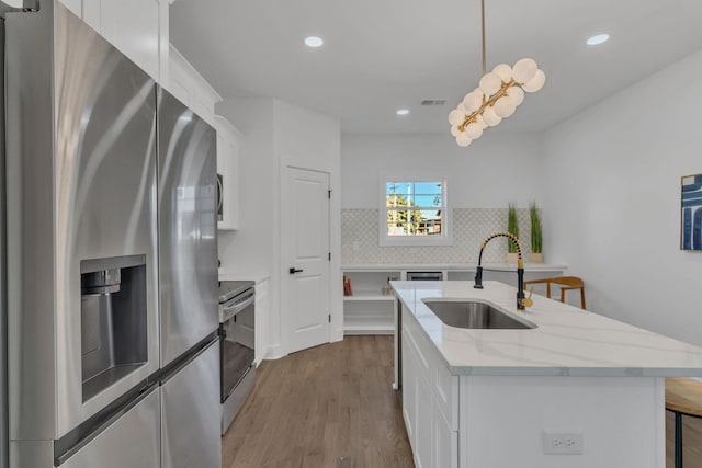 kitchen with decorative light fixtures, white cabinets, and appliances with stainless steel finishes