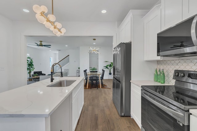 kitchen featuring white cabinetry, stainless steel appliances, a kitchen island with sink, and hanging light fixtures