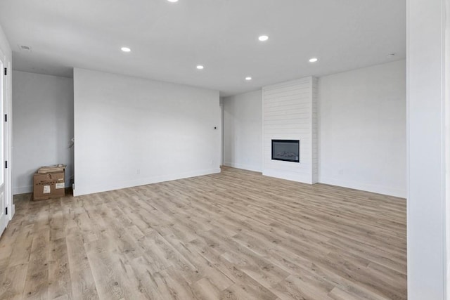 unfurnished living room featuring a large fireplace and light hardwood / wood-style floors