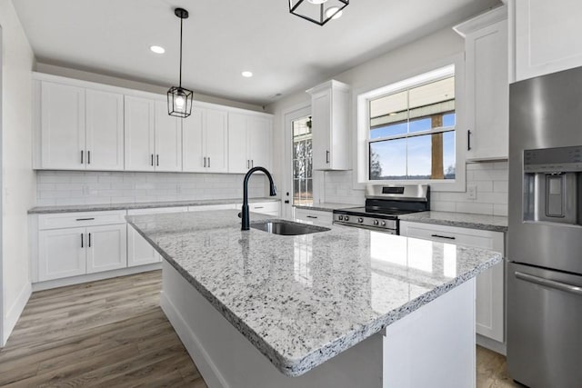 kitchen featuring white cabinetry, appliances with stainless steel finishes, and an island with sink