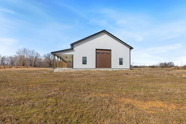 view of outbuilding with a garage, a rural view, and a lawn