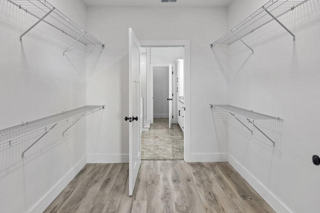 walk in closet with light hardwood / wood-style floors