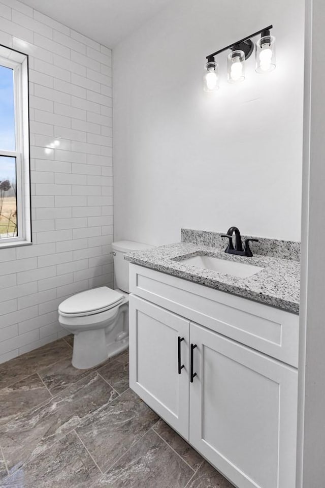 bathroom featuring vanity, tile walls, and toilet
