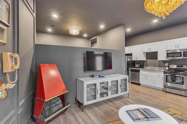 kitchen featuring light wood-type flooring, appliances with stainless steel finishes, sink, and white cabinets