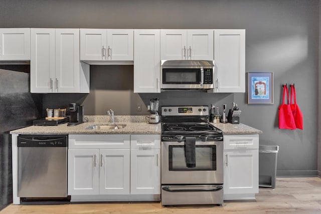 kitchen featuring sink, stainless steel appliances, white cabinets, and light stone countertops