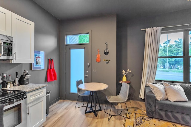 kitchen featuring stainless steel appliances, light stone countertops, light wood-type flooring, and white cabinets