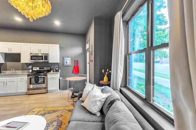 living room featuring an inviting chandelier, sink, and light hardwood / wood-style flooring