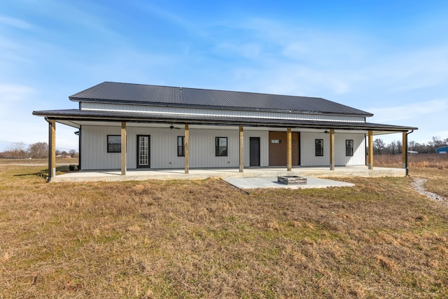 back of property featuring a fire pit, a patio area, ceiling fan, and a lawn