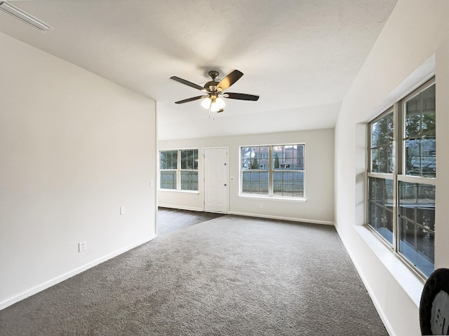 empty room featuring ceiling fan and dark colored carpet