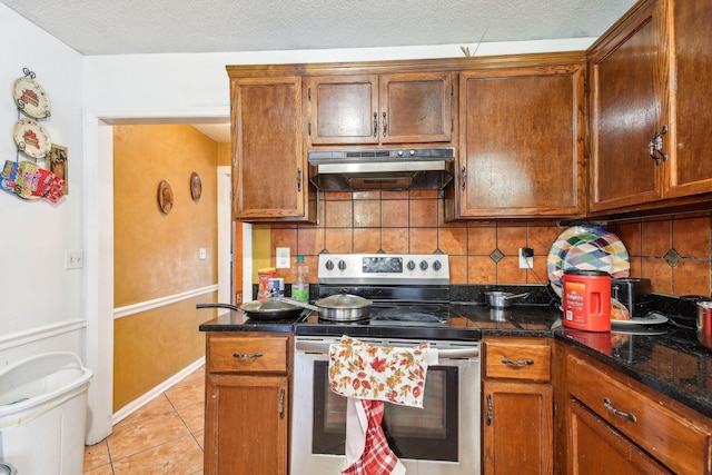 kitchen featuring tasteful backsplash, light tile patterned floors, electric range, and dark stone countertops