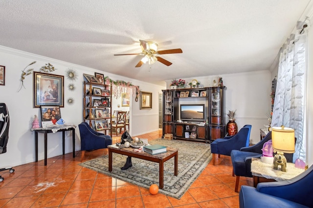 living room with ornamental molding, ceiling fan, tile patterned floors, and a textured ceiling