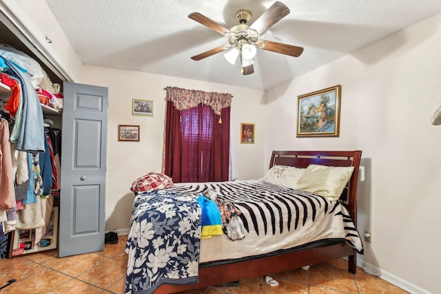 tiled bedroom with ceiling fan, a textured ceiling, and a closet