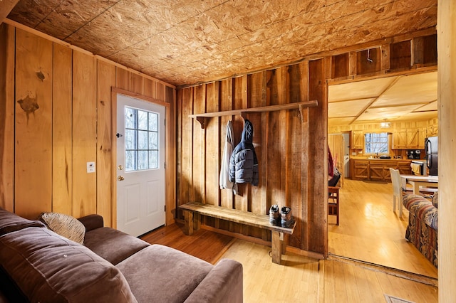 mudroom with light hardwood / wood-style floors and wood walls