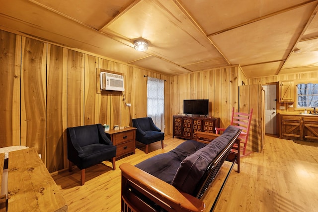 living room featuring sink, light hardwood / wood-style flooring, a wall unit AC, and wooden walls