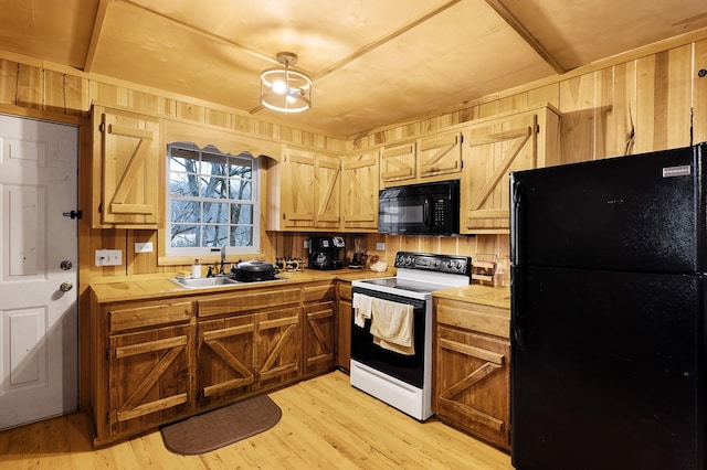 kitchen with sink, tile counters, wood walls, and black appliances