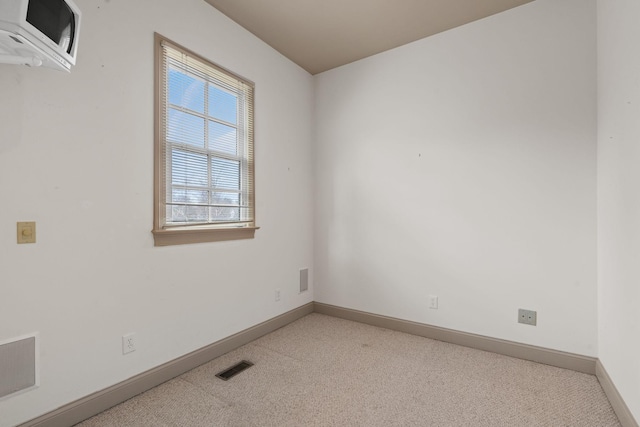 spare room with light carpet and an AC wall unit