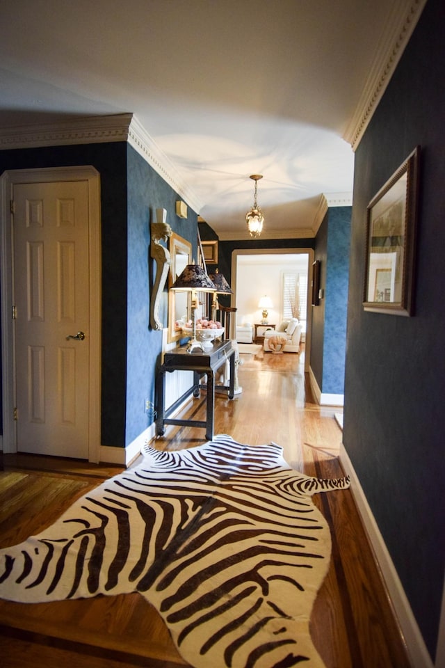 corridor featuring crown molding, hardwood / wood-style floors, and a notable chandelier