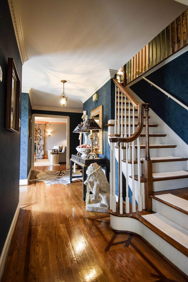 stairs with a notable chandelier, hardwood / wood-style flooring, and ornamental molding