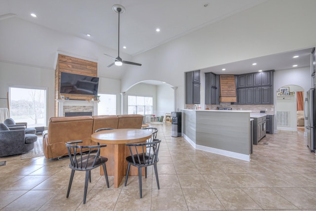 tiled dining area with ceiling fan and a high ceiling