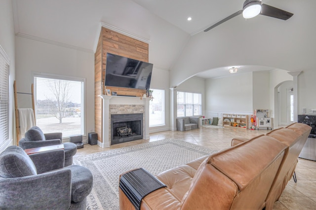 tiled living room with crown molding, a fireplace, high vaulted ceiling, and ceiling fan