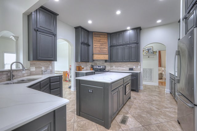 kitchen featuring sink, decorative backsplash, a center island, and appliances with stainless steel finishes