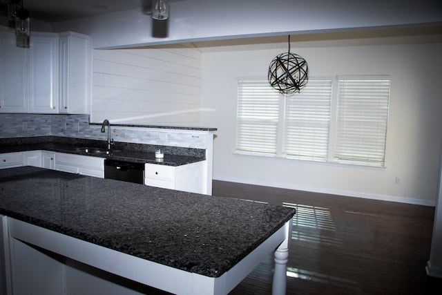 kitchen with dishwasher, sink, white cabinets, dark stone counters, and hanging light fixtures