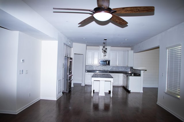 kitchen with tasteful backsplash, hanging light fixtures, a kitchen island, stainless steel appliances, and white cabinets