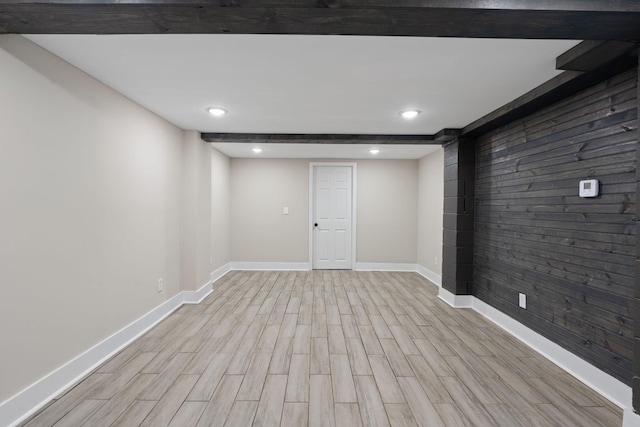 finished below grade area featuring light wood-type flooring, wood walls, baseboards, and recessed lighting