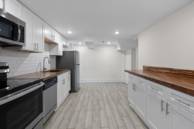 kitchen featuring appliances with stainless steel finishes, white cabinets, and wooden counters