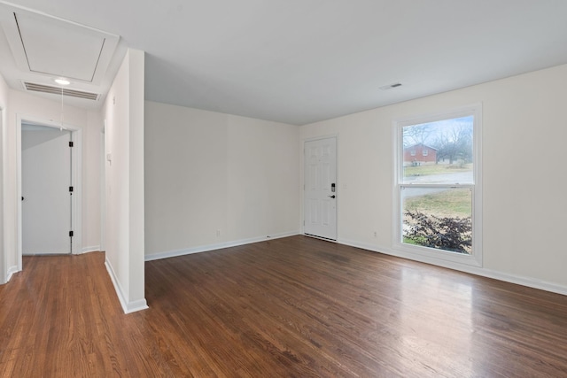 spare room featuring visible vents, dark wood finished floors, attic access, and baseboards