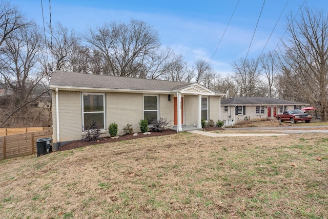 ranch-style house featuring central AC unit, brick siding, a shingled roof, fence, and a front yard