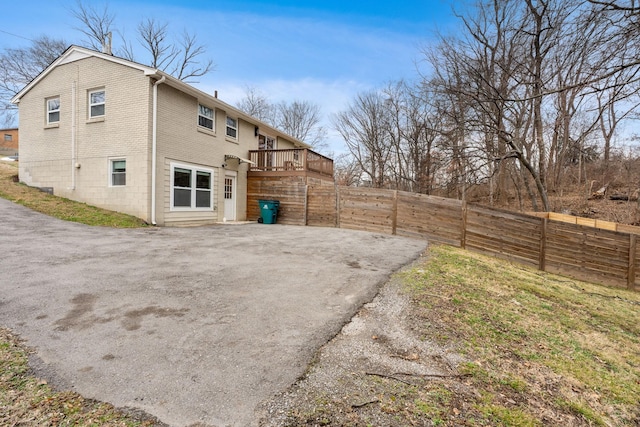 back of property with brick siding, fence, and a wooden deck