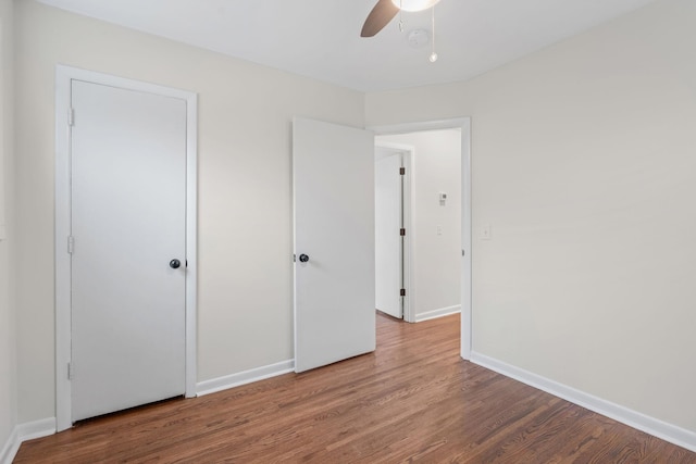 unfurnished bedroom with a ceiling fan, baseboards, and wood finished floors