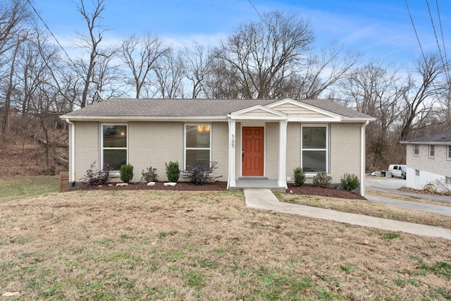 ranch-style house featuring a front lawn, roof with shingles, and brick siding