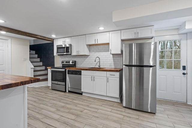 kitchen featuring a sink, stainless steel appliances, wood counters, and white cabinets