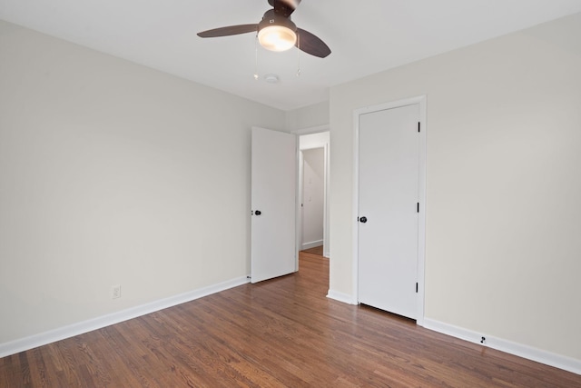 unfurnished room featuring ceiling fan, baseboards, and dark wood-type flooring