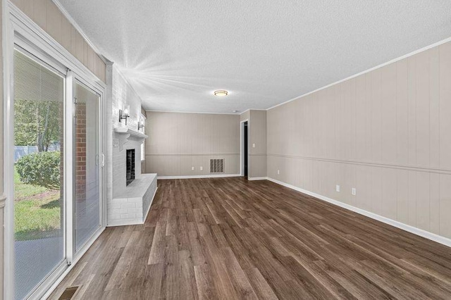 unfurnished living room featuring a brick fireplace, crown molding, and wood-type flooring