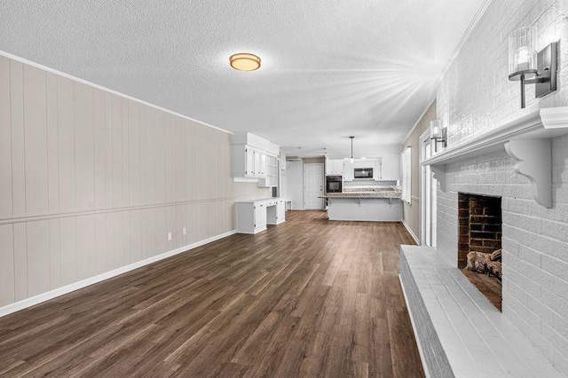 unfurnished living room featuring ornamental molding, a brick fireplace, dark hardwood / wood-style floors, and a textured ceiling