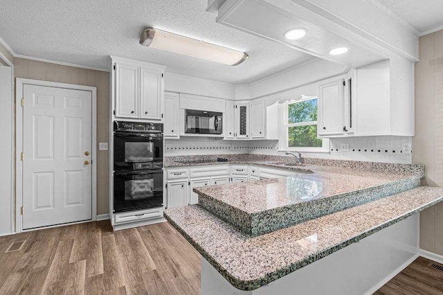 kitchen featuring white cabinets, ornamental molding, kitchen peninsula, and black appliances