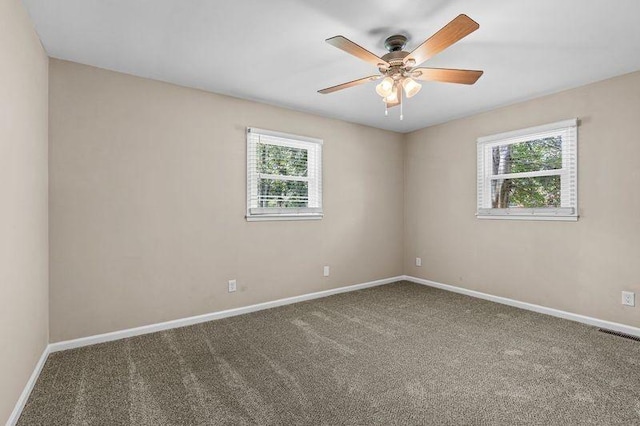 carpeted spare room featuring a wealth of natural light and ceiling fan