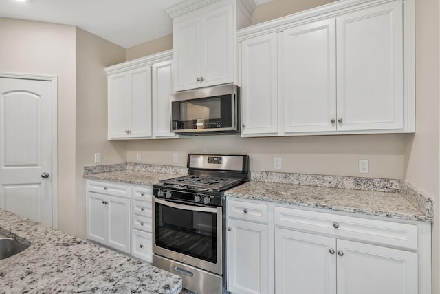 kitchen featuring light stone countertops, stainless steel appliances, and white cabinets