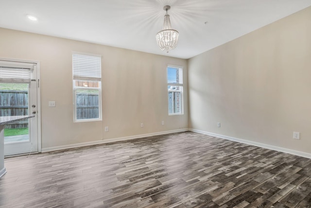 spare room featuring dark wood-type flooring and a chandelier