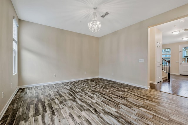 unfurnished room with hardwood / wood-style flooring and a chandelier